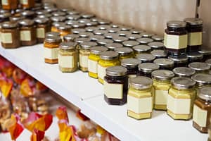 Étagère de bocaux alimentaires avec étiquettes personnalisées vierges, parfaits pour produits faits maison comme confitures, moutardes et sauces – exemple de packaging artisanal.